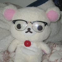 a photo i took of my korillakkuma plush sitting on a bed wearing my glasses